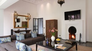 A modern living room with a sofa, coffee table, and a fireplace. - YALI, private house in the heart of the Four Seasons Resort Marrakech (Marrakech)