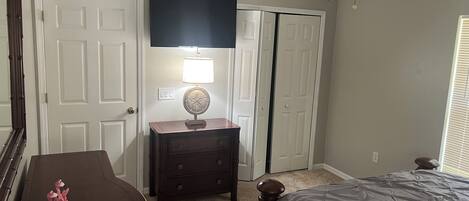 A bedroom with a bed, dresser, lamp, and a ceiling fan.