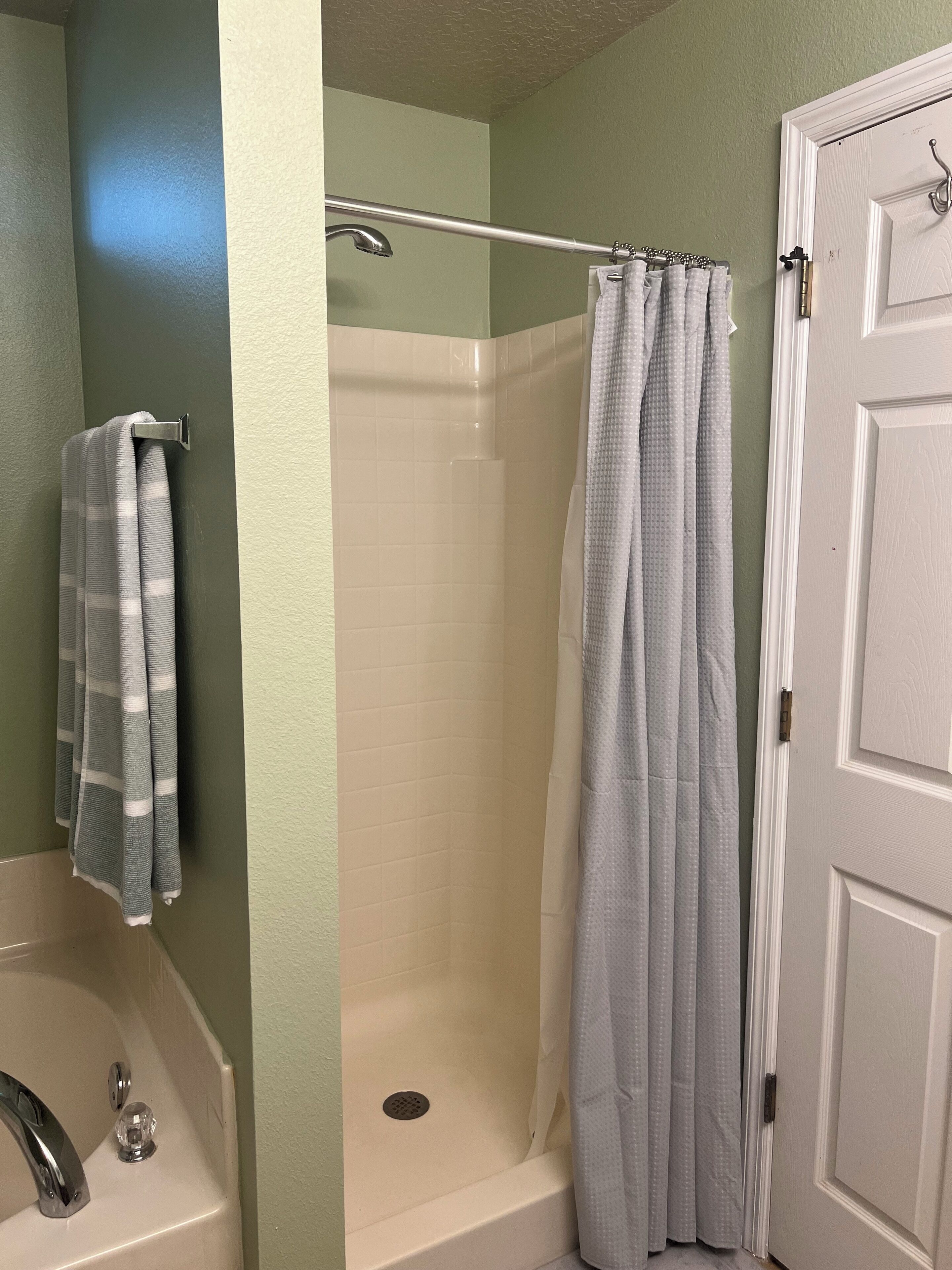 A bathroom with a shower, a bathtub, and a towel rack.