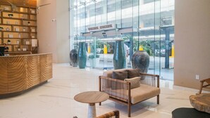 A lobby with a reception desk, seating area, and large windows overlooking a parking garage. - 🌴 Luxury Beachfront Apartment in Mazatlan's Golden Zone - Pool & Oceanfront (Mazatlán)