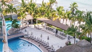 A pool area with lounge chairs and umbrellas, surrounded by palm trees and a view of the ocean. - 🌴 Luxury Beachfront Apartment in Mazatlan's Golden Zone - Pool & Oceanfront (Mazatlán)