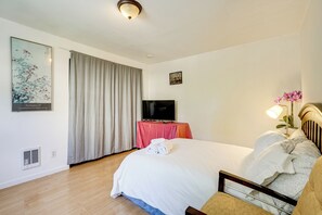 Habitación de hotel con una cama grande, un televisor de pantalla plana, una mesa con mantel rojo y un cuadro en la pared.