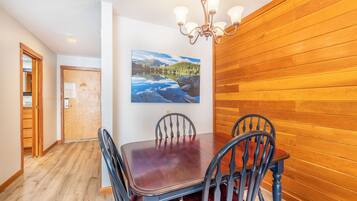 Un comedor con pared de madera, una araña y un cuadro de un lago.