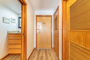 Un pasillo con puertas de madera, un armario de madera y piso de baldosas.