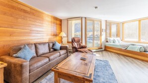 A cozy living room with a brown leather sofa, a wooden coffee table, and a window seat with a view. - Ls1489-0 (Keystone)