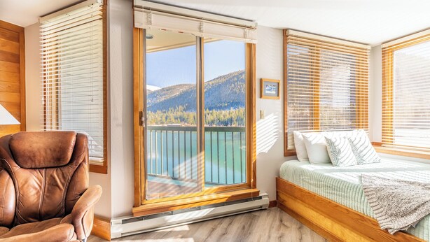 A bedroom with a bed, a chair, and a sliding glass door leading to a balcony with a mountain view. - Ls1489-0 (Keystone)