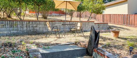 A patio area with a table and chairs, a concrete wall, and a wooden fence.