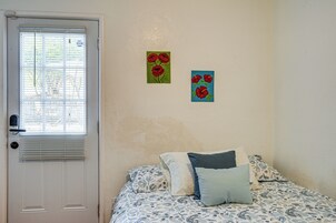 Un dormitorio con una cama, una puerta y dos cuadros en la pared.