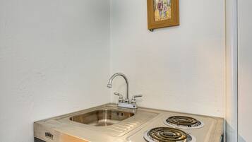 A kitchen with a stainless steel sink and two burners.