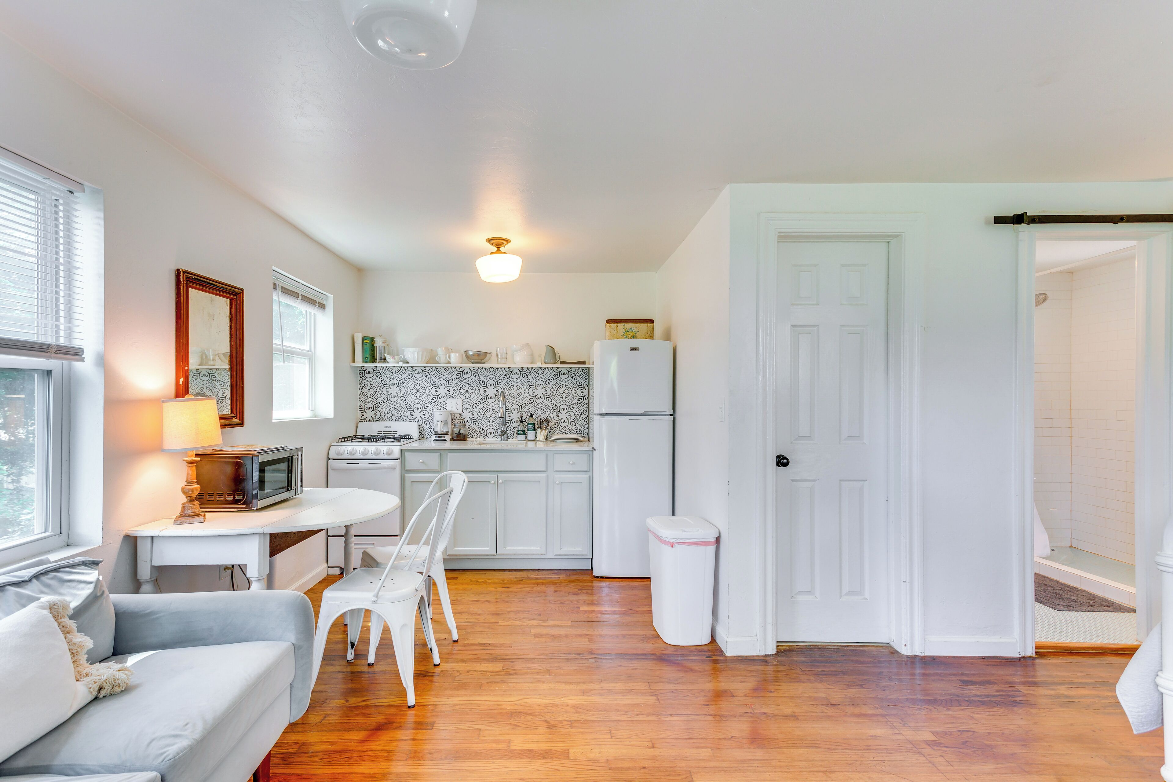 Un espacio habitable compacto con kitchenette, un comedor con mesa y sillas, y una pequeña sala de estar con sofá.