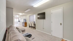 Una sala de estar moderna con un sofá color beige, un televisor de pantalla plana montado en la pared y piso alfombrado.