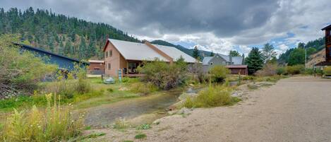 A rural setting with a house, a dirt path, and a stream.