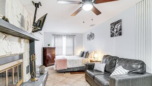 A bedroom with a bed, a grey leather sofa, a fireplace, a ceiling fan, and a wall with a framed picture. - Screened Porch: Tampa Studio 4 Mi to Busch Gardens (Tampa)
