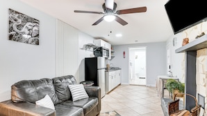 A living room with a leather sofa, a ceiling fan, a kitchen in the background, and a fireplace with a basket. - Screened Porch: Tampa Studio 4 Mi to Busch Gardens (Tampa)