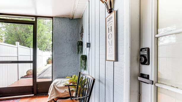 A room with a sliding glass door leading to a patio, a wooden bench, a wall-mounted sign reading "WELCOME TO OUR HOME", and a doorbell. - Screened Porch: Tampa Studio 4 Mi to Busch Gardens (Tampa)