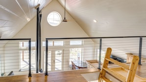 Un loft espacioso con techos altos, ventanas grandes y piso de madera.