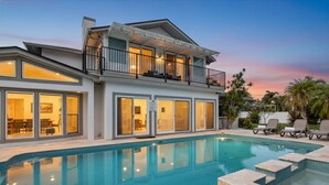 A modern two-story house with a swimming pool, large windows, and a balcony. - Waterfront Oasis – 6BR Home w/ Pool, Spa & kayaks (Largo)