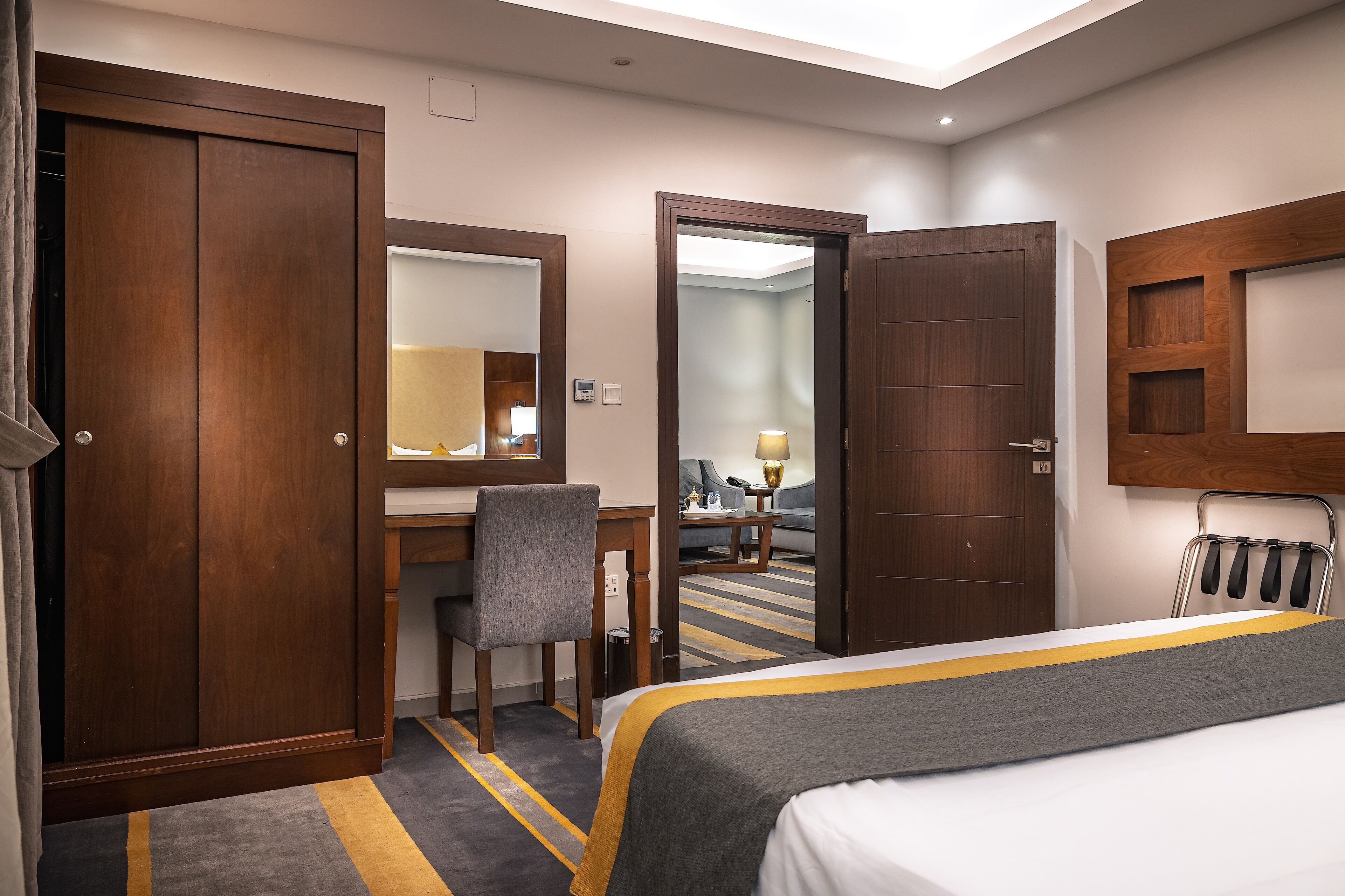 Ein Hotelzimmer mit Bett, Schreibtisch, Stuhl, Spiegel und Kleiderschrank.