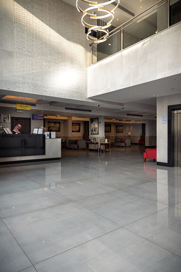 A spacious lobby with a reception desk, seating area, and a modern chandelier.