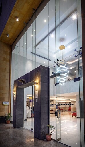 A modern lobby with glass walls, a central column, and a spiral light fixture.