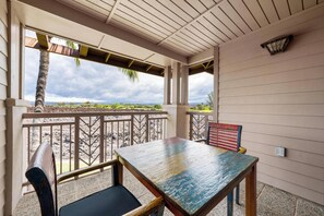 A covered outdoor seating area with a table and chairs, a view of the beach, and a palm tree. - Summer Deal Waikoloa Beach Resort Townhome Sleeps 6 with Hot Tub (Waikoloa)