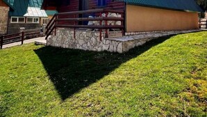 Eine Lodge mit steilem Dach, Steinunterbau und einer Holzterrasse.