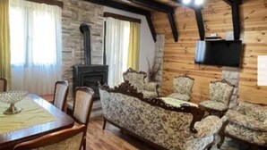 A cozy living room with a stone fireplace, wooden beams, and patterned armchairs. - Cozy Mountain Villa with Stunning Views near Savin Kuk (Žabljak)
