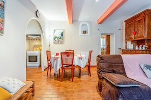 Una sala de estar acogedora con sofá, mesa de comedor, sillas y una zona de cocina con estufa y horno.