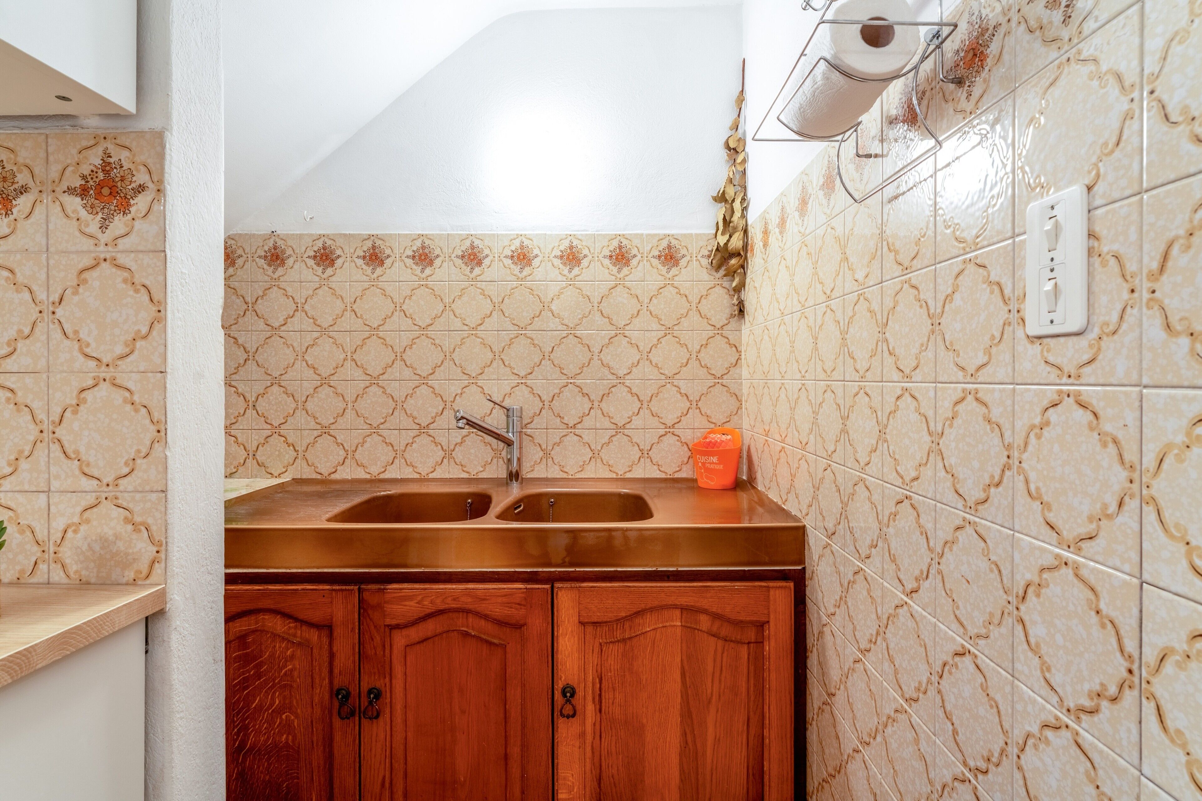 Une cuisine avec deux éviers, des meubles en bois, des carreaux décoratifs et un plafond blanc.