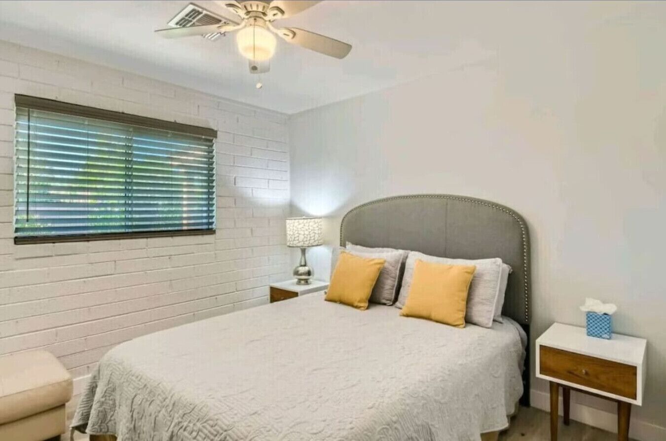 A bedroom with a bed, a nightstand, a lamp, and a ceiling fan.