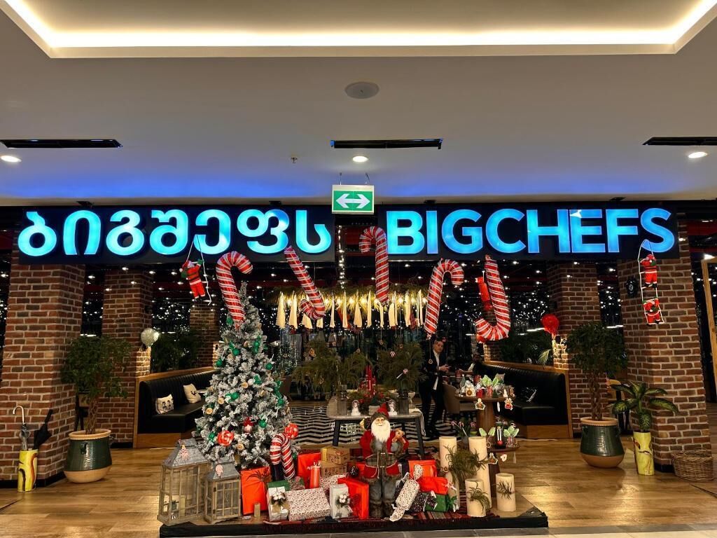 A hotel entrance with a Christmas display, including a decorated tree, candy canes, and a sign reading "BIGCHEFS".