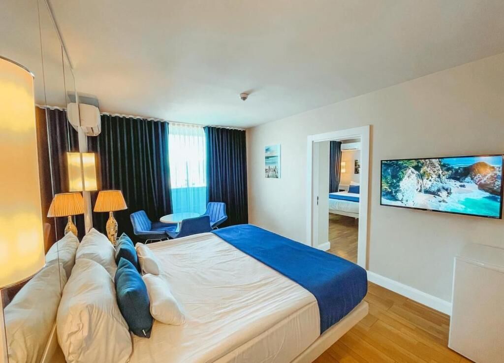 Quarto de hotel com cama, televisão, escrivaninha e cadeira.