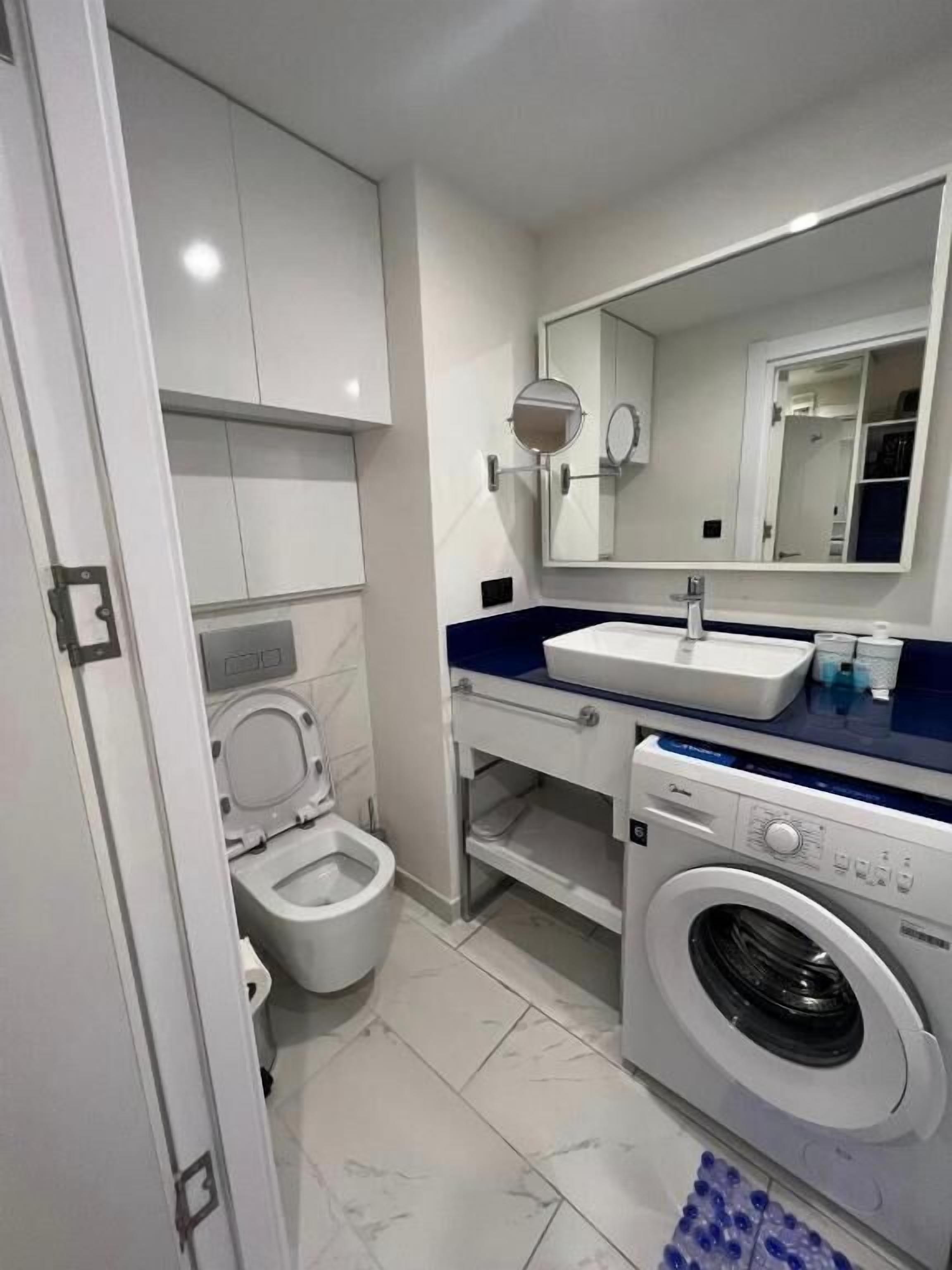 A compact bathroom with a toilet, sink, and washing machine.