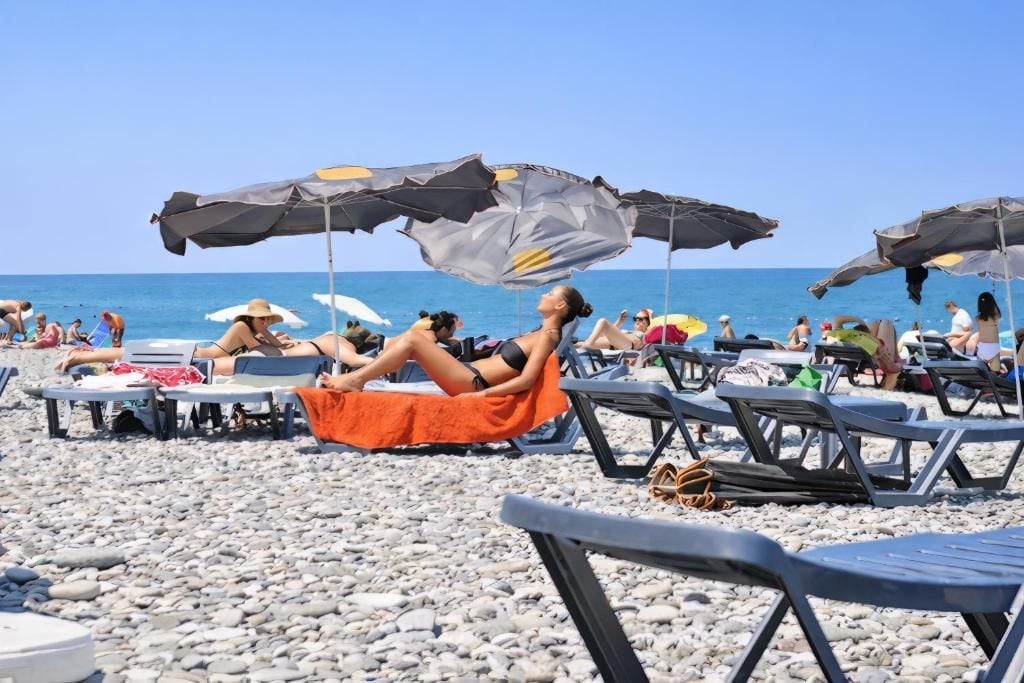 Une plage avec des chaises longues et des parasols, un ciel dégagé et l’océan en toile de fond.
