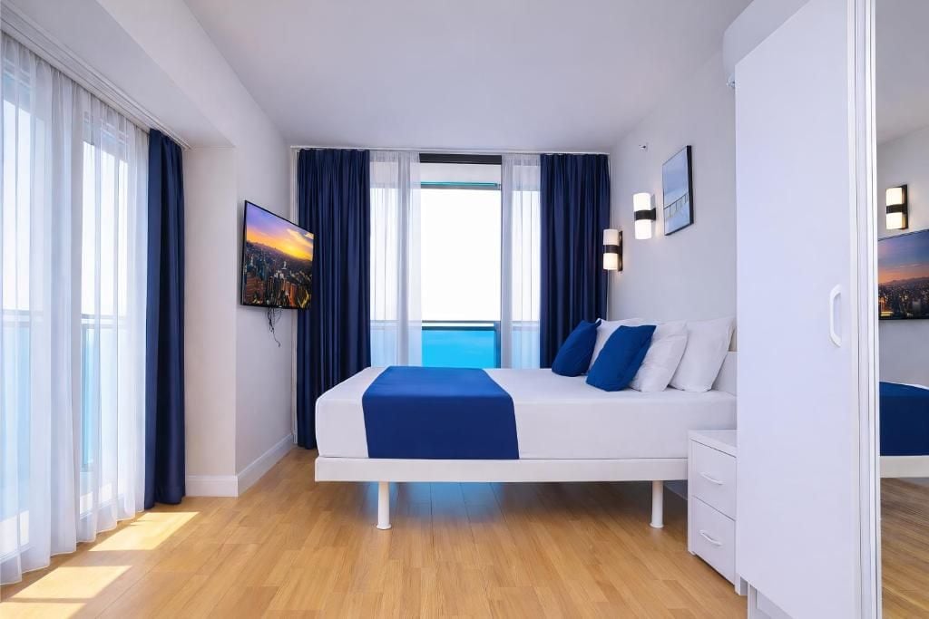 Una habitación de hotel moderna con una cama, televisión y vistas a la ciudad.