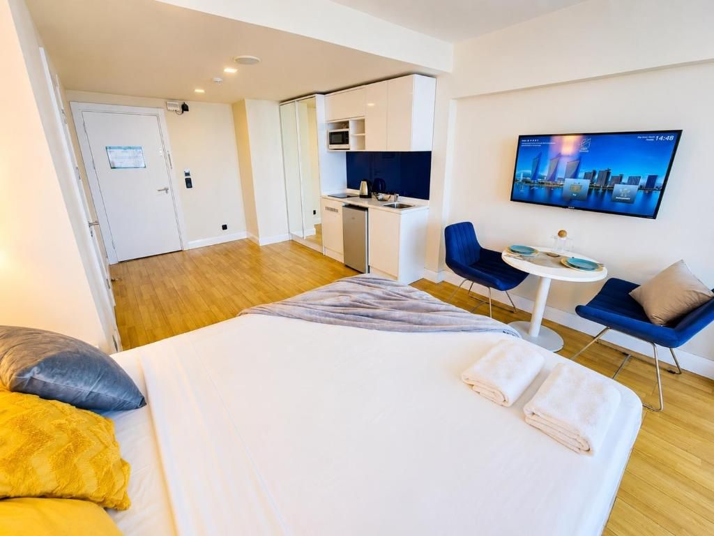 Ein Hotelzimmer mit Bett, Schreibtisch, Stuhl, Fernseher und einer Küchenzeile.