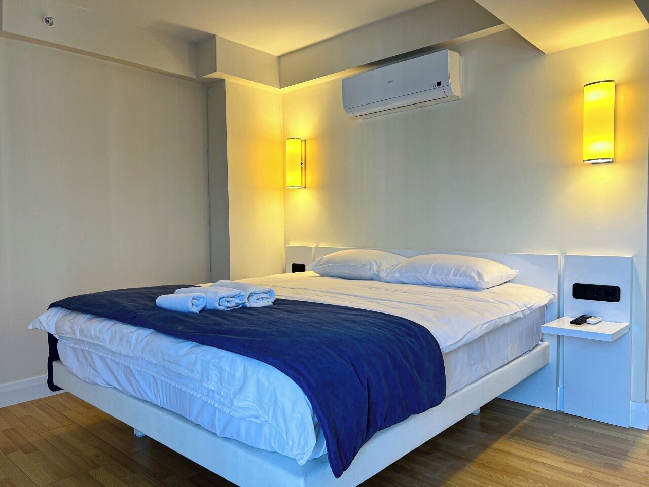 Ein modernes Hotelzimmer mit Bett, Nachttischen und Wand-Klimaanlage.
