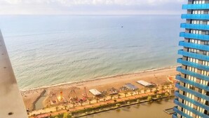 A coastal view with a beach, a pier, and a building with blue balconies. - Holiday in orbi city  (Batumi)