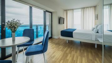 Een moderne hotelkamer met balkon, een bed, bureau met stoel en een bloevas.