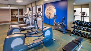 Ein Fitnessstudio mit Laufbändern, Crosstrainern, einer Bank und Kurzhanteln.