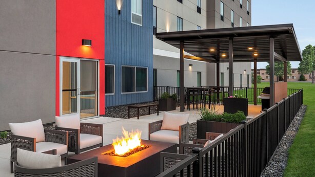 An outdoor seating area with wicker furniture, a fire feature, and a covered patio. - Candlewood Suites Mission East Mcallen Area by IHG (Mission)