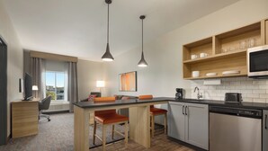 A modern kitchen with a central island, bar stools, a microwave, and a dishwasher. - Candlewood Suites Mission East Mcallen Area by IHG (Mission)