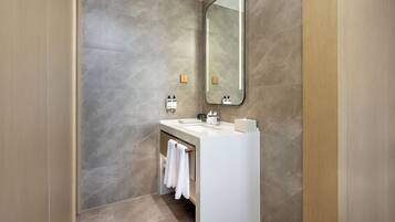 A modern bathroom with a large mirror, a white sink, and a towel rack.