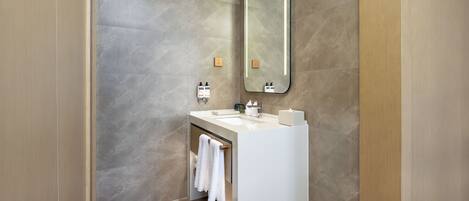 A modern bathroom with a large mirror, a white sink, and a towel rack.