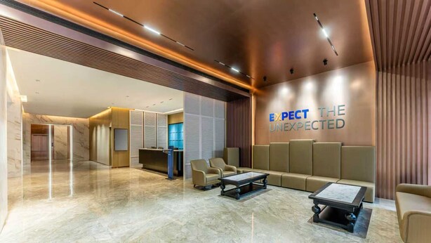 Een moderne lobby met een marmeren vloer, zithoeken en een muur waarop staat: 'EXPECT THE UNEXPECTED'.