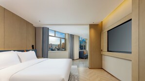 Een moderne hotelkamer met een groot bed, een televisie en uitzicht over de stad.