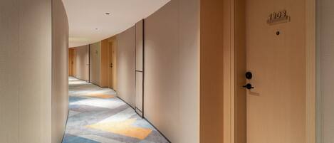 A hotel corridor with wooden doors, numbered 1303, and a patterned carpet.