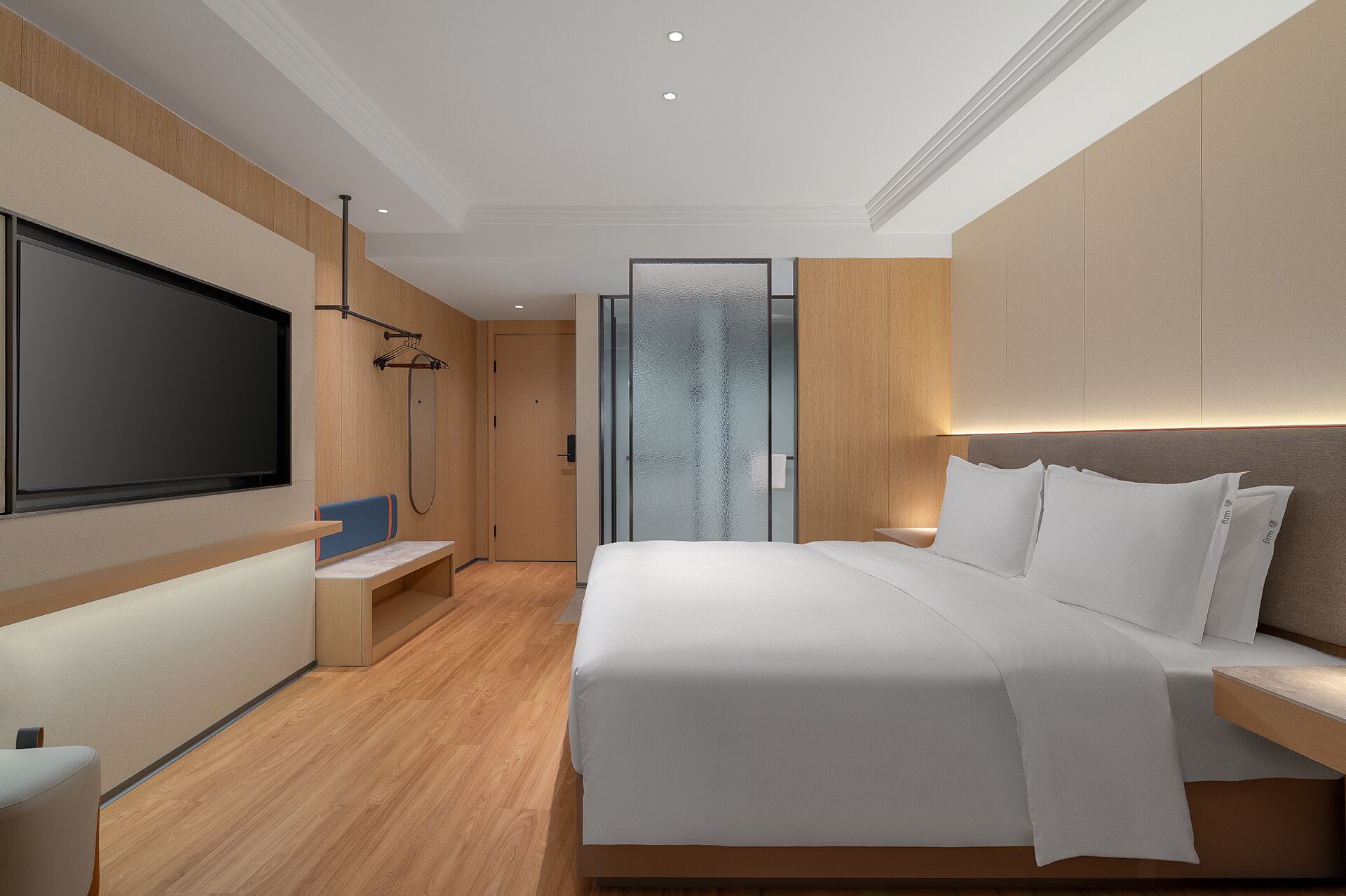 A modern hotel room with a large bed, a flat-screen TV, a seating area, and a shower.
