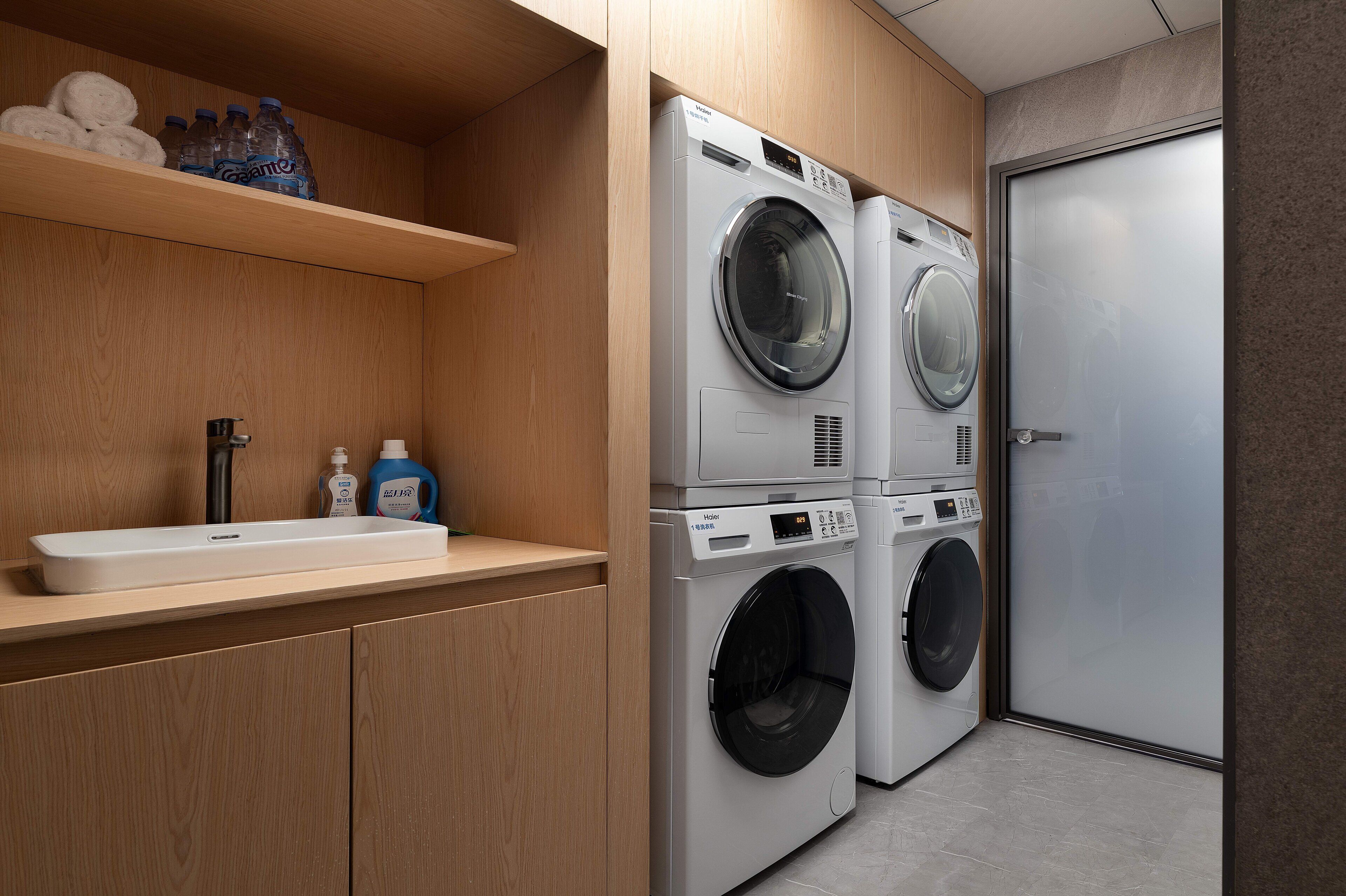 A modern laundry room with two front-loading washing machines, a shelf with toiletries, and a sink.