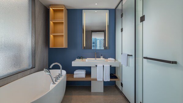 A modern bathroom with a freestanding bathtub, a vanity with a mirror, and a towel rack.